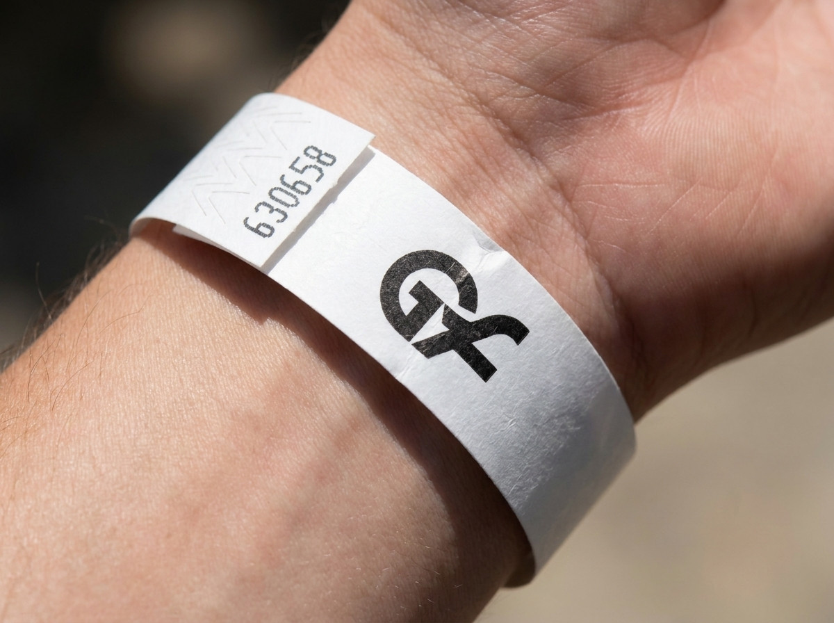 Close-up of a white paper wristband with a color-printed logo, fastened on a wrist