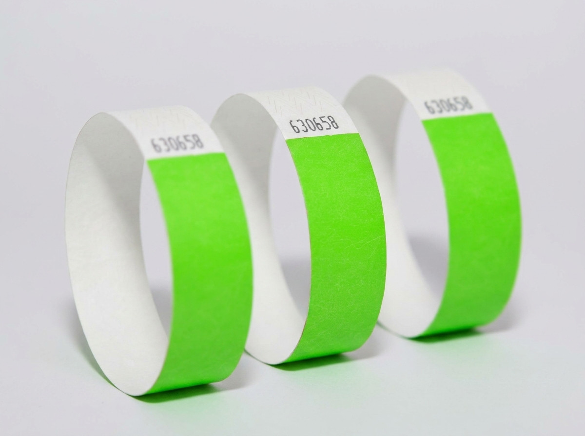 Side-by-side comparison of a coloured Tyvek wristband and an elegant white ID wristband on a light wood background